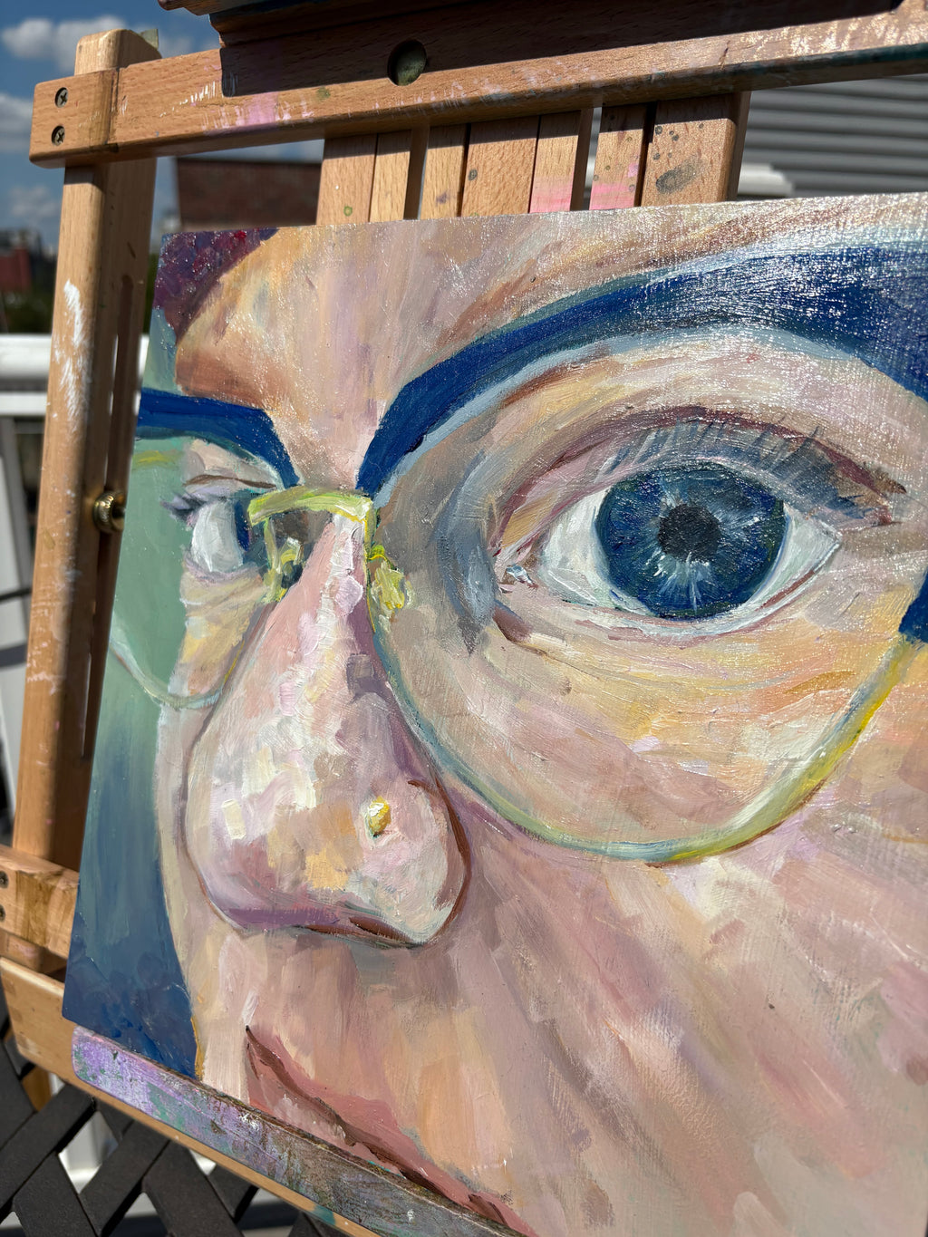 Close up oil painting of the Artist's eyes, she's wearing bright blue cat eye glasses that match her blue eyes
